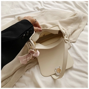 Close-up of the cream shoulder bag interior capacity with decorative silk scarf bow handle