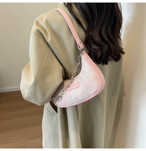 Détail du sac croissant rose montrant le tissu jacquard et la chaîne florale en métal