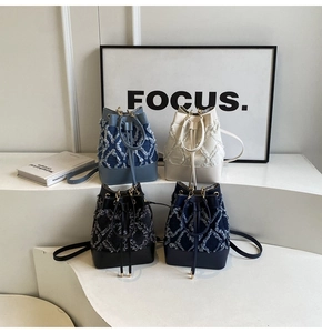Detail of four multi-color bucket bags in denim and leather with tassel stitching