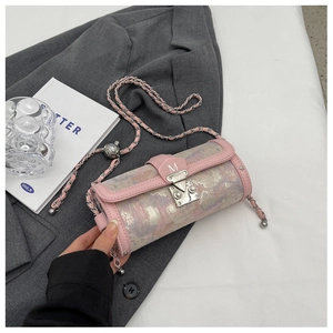 Detailed view of pink leather cylinder bag with metal M-lock on a stylish tabletop