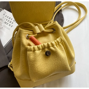Detailed close-up of yellow pebbled leather backpack showing drawstring and magnetic pocket