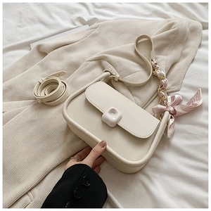 Close-up of cream square shoulder bag with smooth texture and decorative silk scarf