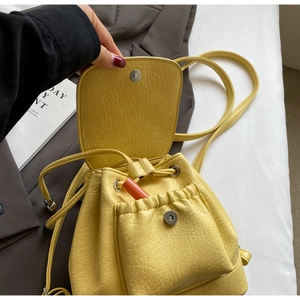 Detail of bright yellow pebbled leather bucket backpack with drawstring and magnetic closure