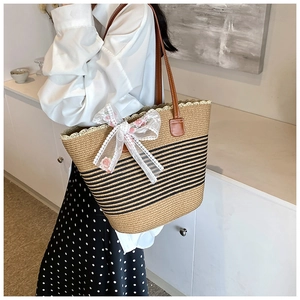 Close-up of woven straw tote bag featuring white lace bow and pink floral embroidery