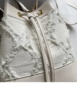 Detail of cream denim bucket bag with quilted rhombic pattern and leather drawstring