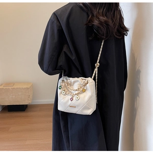 Détail du sac seau blanc matelassé avec chaînes dorées et pendentifs en émail coloré