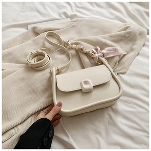 Detail of cream-colored crossbody bag with trendy silk scarf and square buckle accent