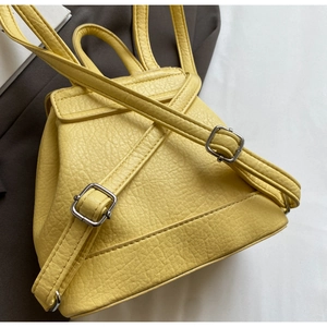 Detail of bright yellow leather backpack with lychee grain texture and silver buckles