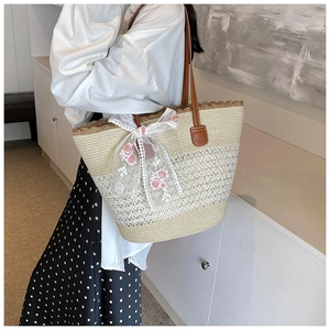 Detail of woven straw tote bag with lace floral bow and brown leather shoulder strap