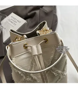 Detail of cream bucket bag showing drawstring closure and frayed canvas texture