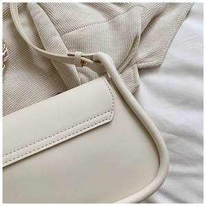 Detail of premium cream leather texture and neat stitching on minimalist shoulder bag