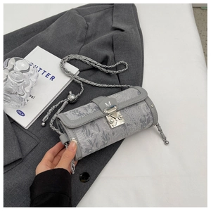 Detail of grey cylindrical bag with leaf prints, silver chain strap, and M-logo buckle