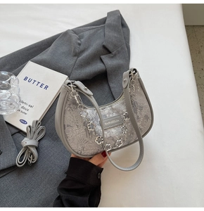 Détail du sac hobo en jacquard floral gris avec chaîne à fleurs argentée et cuir