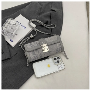 Detail of grey cylinder bag with jacquard fabric, chain strap and silver M buckle