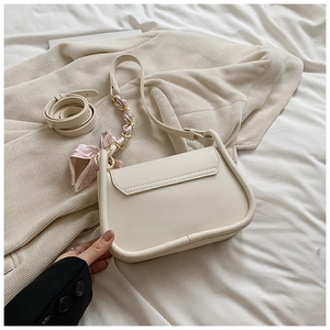 Detail of cream saddle bag with silk scarf metal chain and adjustable long shoulder strap
