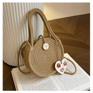 Detailed macro view of woven straw round bag with wooden button and heart tag detail