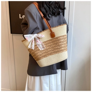 Close-up of woven straw tote bag featuring white lace bow and pink floral embroidery details