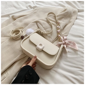 Detailed view of cream PU crossbody bag with silk scarf chain strap and pompom charm