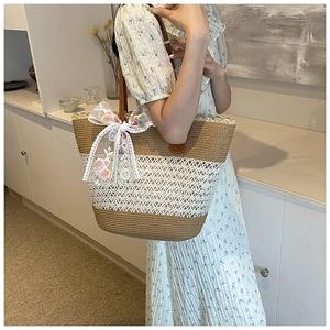 Straw woven tote bag with white lace bow and floral embroidery shown on model