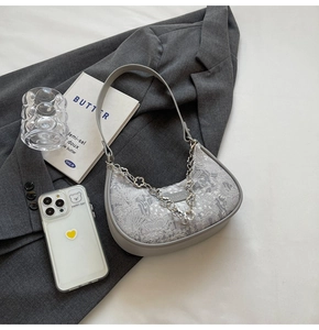 Détail d'un sac hobo vintage gris avec chaîne en argent fleurie et broderies