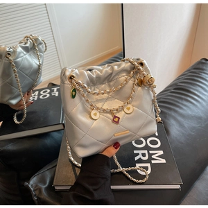 Détail du sac seau matelassé argenté avec breloques colorées et bandoulière dorée