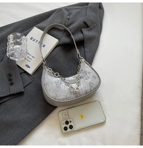 Détail du sac sous le bras en jacquard floral gris avec chaîne décorative en métal argenté