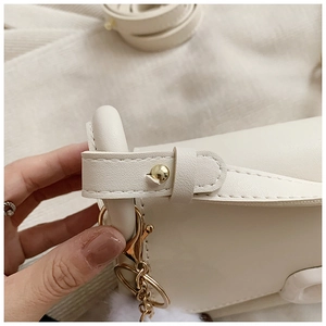 Close-up of cream PU leather shoulder bag with gold hardware and plush ball charm
