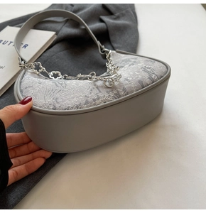 Détail du sac demi-lune en jacquard gris avec chaîne décorative à fleurs argentées