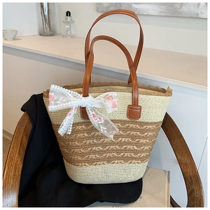 Detail of woven straw tote bag with white lace bow and floral embroidery details