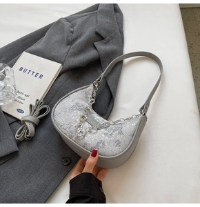 Détail du sac dumpling gris en jacquard avec chaîne florale argentée et sangle
