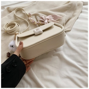 Detail of cream white crossbody bag with striped silk scarf and fuzzy pompom charm
