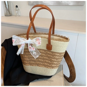 Detail of woven straw tote bag with large floral lace bow and brown leather handles