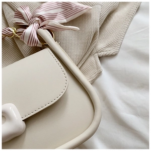 Detail of off-white leather bag with golden chain and striped silk scarf accessory