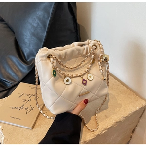 Détail du sac seau matelassé crème avec fermeture à cordon et breloques cœur dorées