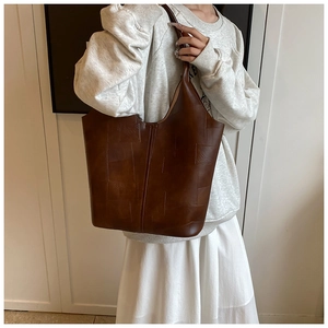 Gros plan sur un sac cabas en cuir marron foncé avec coutures géométriques texturées