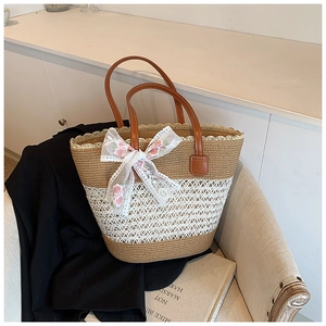 Detail of hand-woven straw tote featuring delicate white lace bow and floral embroidery