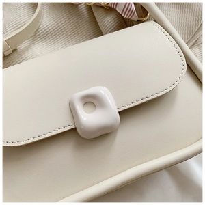 Close-up of cream PU leather shoulder bag with decorative buckle and silk scarf detail