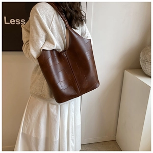 Détail d'un grand sac cabas marron avec patchwork géométrique porté par un mannequin