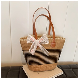 Close-up of handwoven straw tote bag with floral lace bow and black striped pattern