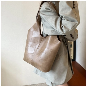 Sac fourre-tout en cuir marron à motifs patchwork porté par un mannequin en costume