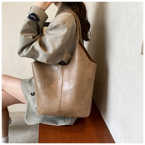 Grand sac cabas kaki en cuir gaufré porté à l'épaule par un mannequin en studio