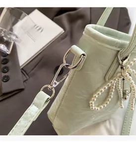Detail of light green embossed leather bucket bag with silver hardware and pearl strap