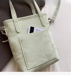 Detail of mint green bucket bag with marble texture, pearl charm and functional pocket