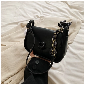 Detail of black crossbody bag with silk scarf ribbon and gold chain shoulder strap