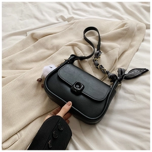 Detail of black faux leather crossbody bag with silk scarf strap and plush bear charm