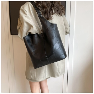 Vue arrière d'un mannequin portant un grand cabas noir géométrique en patchwork de cuir