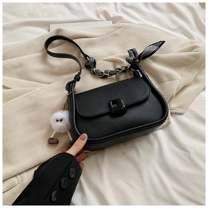 Detail of black saddle bag with silk scarf chain handle and plush monster charm