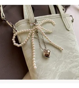 Detail of mint green bucket bag with wrinkled texture and large pearl bow accessory