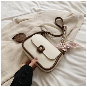 Chic cream crossbody bag on beige knitwear with striped scarf detail and brown strap