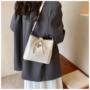 Secchiello crema chic con fiocco di perle mostrato con un outfit alla moda attuale